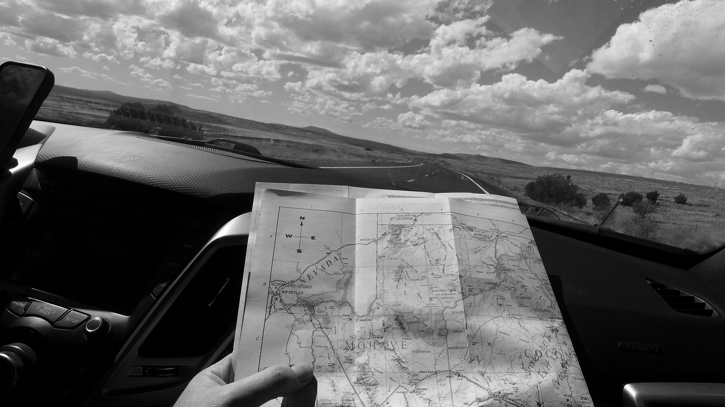 Een wegenkaart in een auto met uitzicht op een lange weg door een open landschap